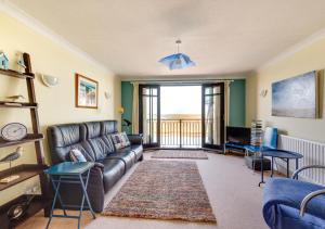 a living room with a leather couch and a television at Flat 8 The Granary in Wells next the Sea