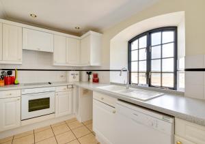a white kitchen with a sink and a window at Flat 8 The Granary in Wells next the Sea