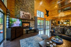 a living room with a tv and a stone wall at Hickory Bear - Cabin surrounded by pines, Sleeps 10, Hot Tub, Fire Pit, Arcade, Foosball Table & Deck Slide in Broken Bow