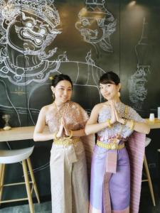 two women standing in a pose in front of a wall at YAKTHAI POSHTEL in Bangkok