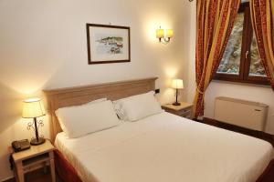 a bedroom with a bed with two lamps and a window at Mercure Argentario Hotel Filippo II in Porto Santo Stefano