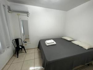 a small bedroom with a bed and a chair at AP - Os Três Pandeiros in Campina Grande