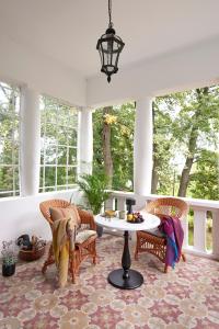 - une terrasse couverte avec des chaises en osier et une table dans l'établissement Villa Chez les Amis - Adults only, à Balatonszepezd