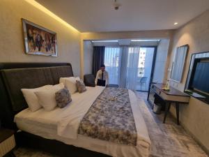 una habitación de hotel con una cama grande con una persona de pie en la puerta en Reggenza Hotel Downtown Ramallah en Ramallah