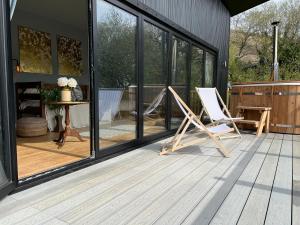 a deck with two rocking chairs on a house at Luxury Lodge In The Treetops in Llanbrynmair