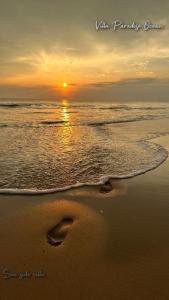 a sunset on the beach with footprints in the sand at Villa Paradise Ocean in Bentota