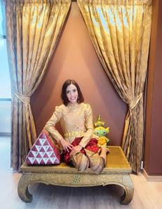 a woman sitting on a bed in a room at YAKTHAI POSHTEL in Bangkok