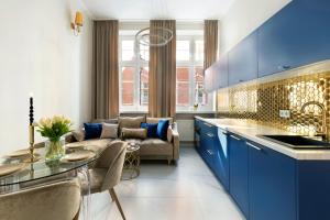 a kitchen and living room with blue cabinets and a couch at Old Town Premium by Elite Apartments in Gdańsk