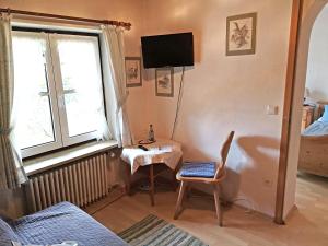 Sala de estar con silla, mesa y TV en Pension Brucker, en Aschau im Chiemgau