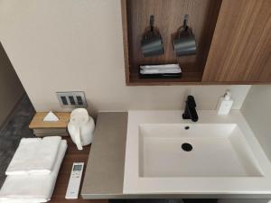 a bathroom with a large white sink and towels at ICHIYU HOTEL ASAKUSA in Tokyo