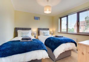 um quarto com 2 camas e cobertores azuis em 1 Street Farm Cottages em Bodham
