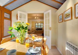 uma sala de jantar com uma mesa com um vaso de flores em 1 Street Farm Cottages em Bodham