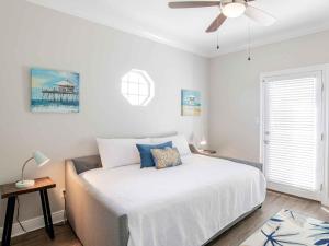 Un dormitorio blanco con una cama y un ventilador de techo. en Sunglow Bungalow, en Pensacola Beach