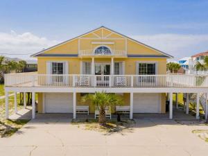 Casa amarilla grande con balcón blanco en Sunglow Bungalow, en Pensacola Beach