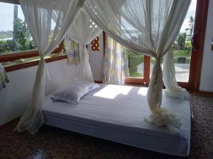 uma cama com cortinas brancas num quarto com uma janela em Mentawai Balcony em Masokut