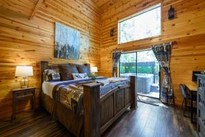 ein Schlafzimmer mit einem Bett in einem Blockhaus in der Unterkunft Hickory Bear - Cabin surrounded by pines, Sleeps 10, Hot Tub, Fire Pit, Arcade, Foosball Table & Deck Slide in Broken Bow