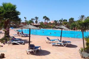 a large pool with people laying in chairs and umbrellas at Apartment Cumbre Vieja Fuerteventura in Corralejo