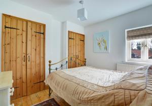 East Rudham的住宿－17 The Green，一间卧室设有一张床、木制橱柜和窗户。