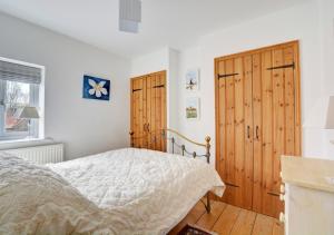1 dormitorio con cama y puertas de madera en 18 The Green, en East Rudham
