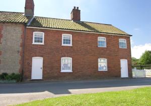 a red brick house with white doors on a street at 18 The Green in East Rudham