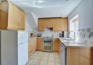 a kitchen with wooden cabinets and a white refrigerator at 18 The Green in East Rudham