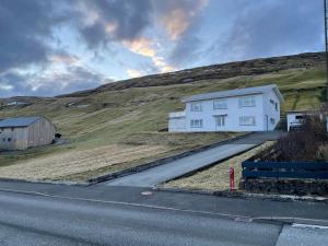 ein weißes Haus an der Seite eines Hügels in der Unterkunft GiljaHome in Sandavágur