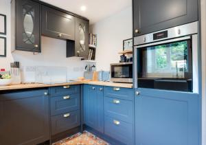 uma cozinha com armários azuis e um micro-ondas em 3 Pond Cottages 