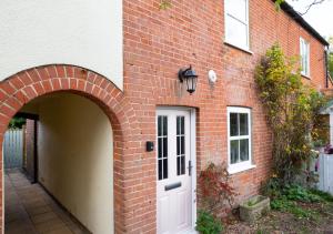 a brick building with a white door and an archway at 3 Pond Cottages 