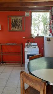 a kitchen with red walls and a table and a stove at Cabaña km 12,7 in San Carlos de Bariloche