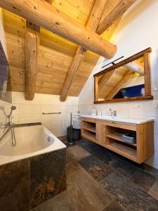 a bathroom with a tub and a sink and wooden ceilings at Almzauber Chalets Hochrindl in Hochrindl