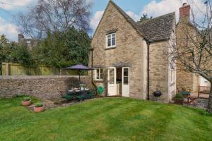 Una antigua casa de piedra con una mesa en el patio. en Peach Cottage, en Poulton