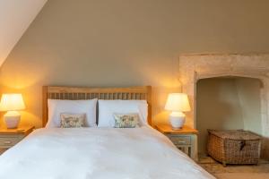 a bedroom with a large white bed with two lamps at Peach Cottage in Poulton