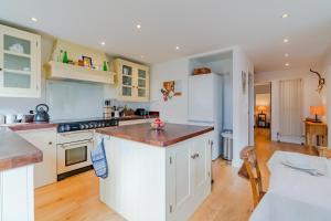 a kitchen with white cabinets and a wooden floor at Peach Cottage in Poulton