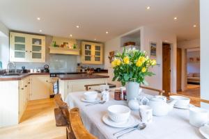 a kitchen with a table with a vase of flowers on it at Peach Cottage in Poulton