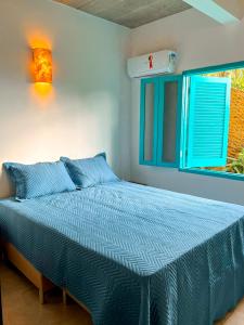 um quarto com uma cama com lençóis azuis e uma janela em Linda casa em condomínio fechado com vista para Ilha das Cabras em Ilhabela