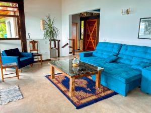 uma sala de estar com um sofá azul e uma mesa de centro em Linda casa em condomínio fechado com vista para Ilha das Cabras em Ilhabela