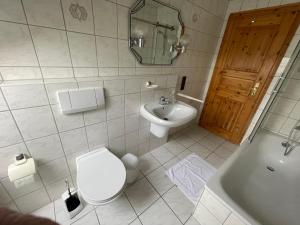 a bathroom with a toilet and a sink and a tub at Ferienwohnung zum Nürburgring in Münk +11 photos