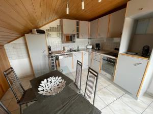 a kitchen with white cabinets and a table with chairs at Ferienwohnung zum Nürburgring in Münk
