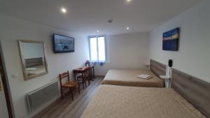 - une chambre avec 2 lits, une table et une fenêtre dans l'établissement Hôtel du Roc, à Castellane
