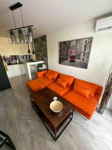 a living room with an orange couch and a table at Przestronna i jasna kawalerka z balkonem in Wrocław