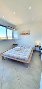 a large bed in a room with two windows at Appartement moderne en bord de mer in Palavas-les-Flots