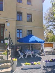 a table with a blue umbrella in front of a building at Willa Pod Gwiazdami & SPA in Kudowa-Zdrój