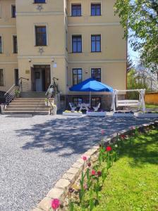 ein Gebäude mit einem blauen Regenschirm und ein paar Blumen in der Unterkunft Willa Pod Gwiazdami & SPA in Kudowa-Zdrój