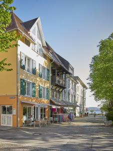 een rij gebouwen op een straat met tafels en stoelen bij SEEMOMENTE Überlingen an der Promenade in Überlingen