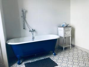 y baño con bañera azul y mesa. en les chambres fleuries, en Saint-Benoît-du-Sault