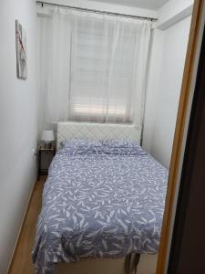 a bedroom with a bed with a blue comforter and a window at Lavander in Banja Luka