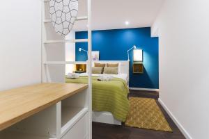 een slaapkamer met een bed en een blauwe muur bij Benfica Apartments I by Homing in Lissabon