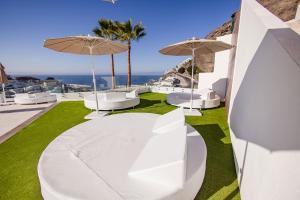 a patio with white chairs and umbrellas and the ocean at Servatur Hartaguna - Adults Only in Puerto Rico de Gran Canaria