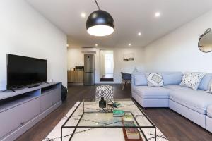 ein Wohnzimmer mit einem blauen Sofa und einem Flachbild-TV in der Unterkunft Benfica Apartments III by Homing in Lissabon