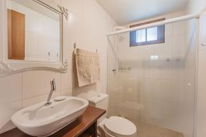 a white bathroom with a sink and a toilet at Casa p/ 4, wifi, ar, gara in Joinville